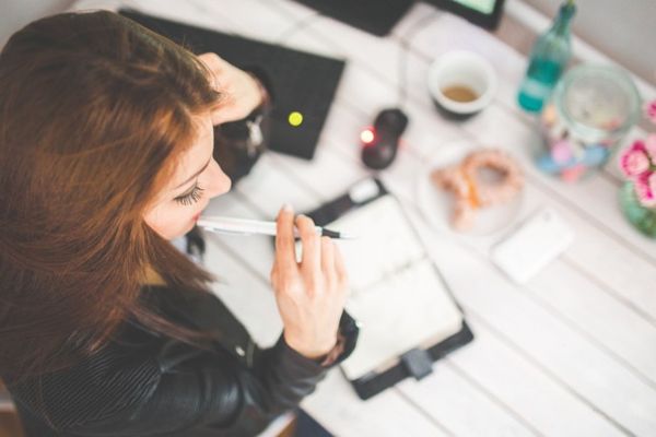 机の前でスケジュール帳を開く女性